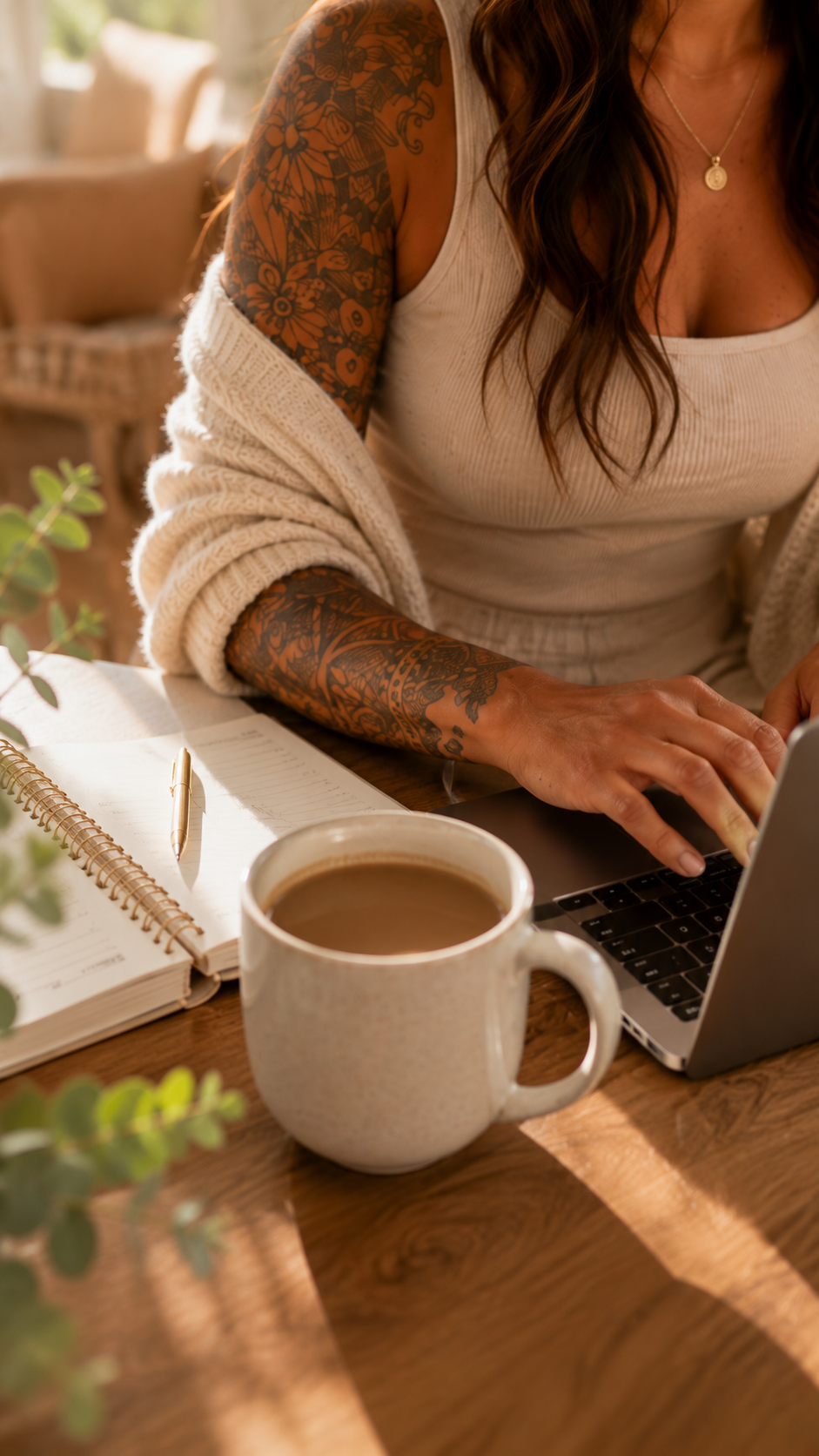Woman writing in a notebook beside her laptop with a warm cup of coffee